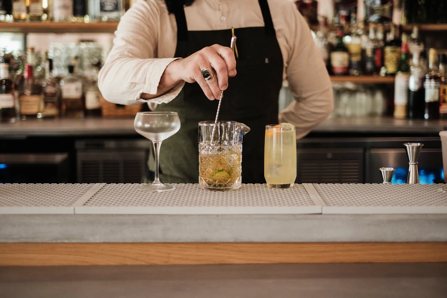 Bartender mixing cocktails behind a well stocked bar
