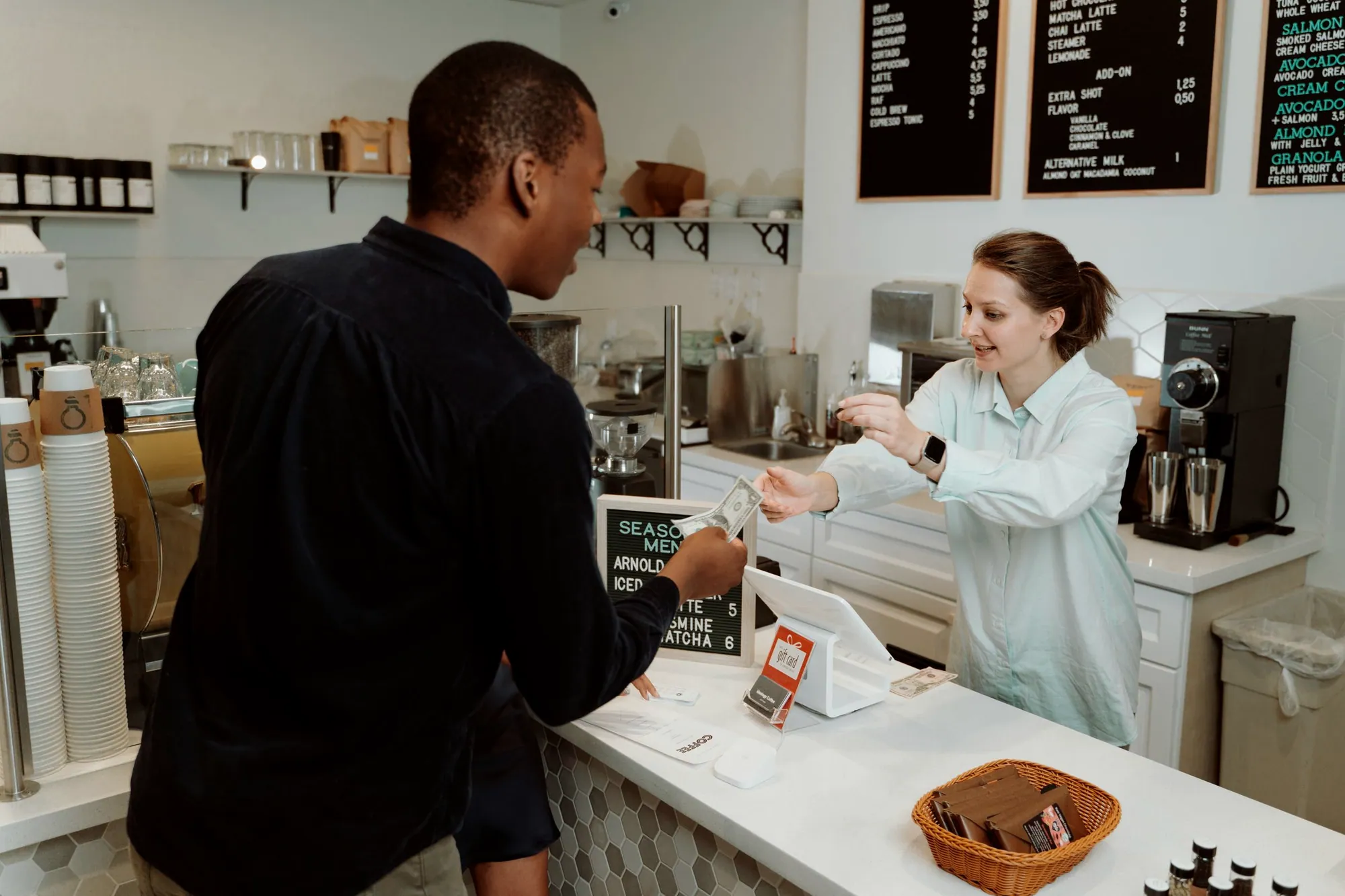Customer paying a barista at a coffee shop counter