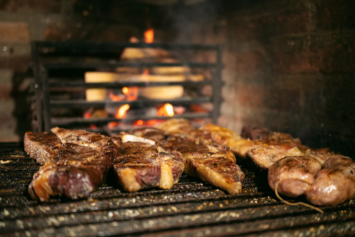 Steaks cooking over an open fire grill