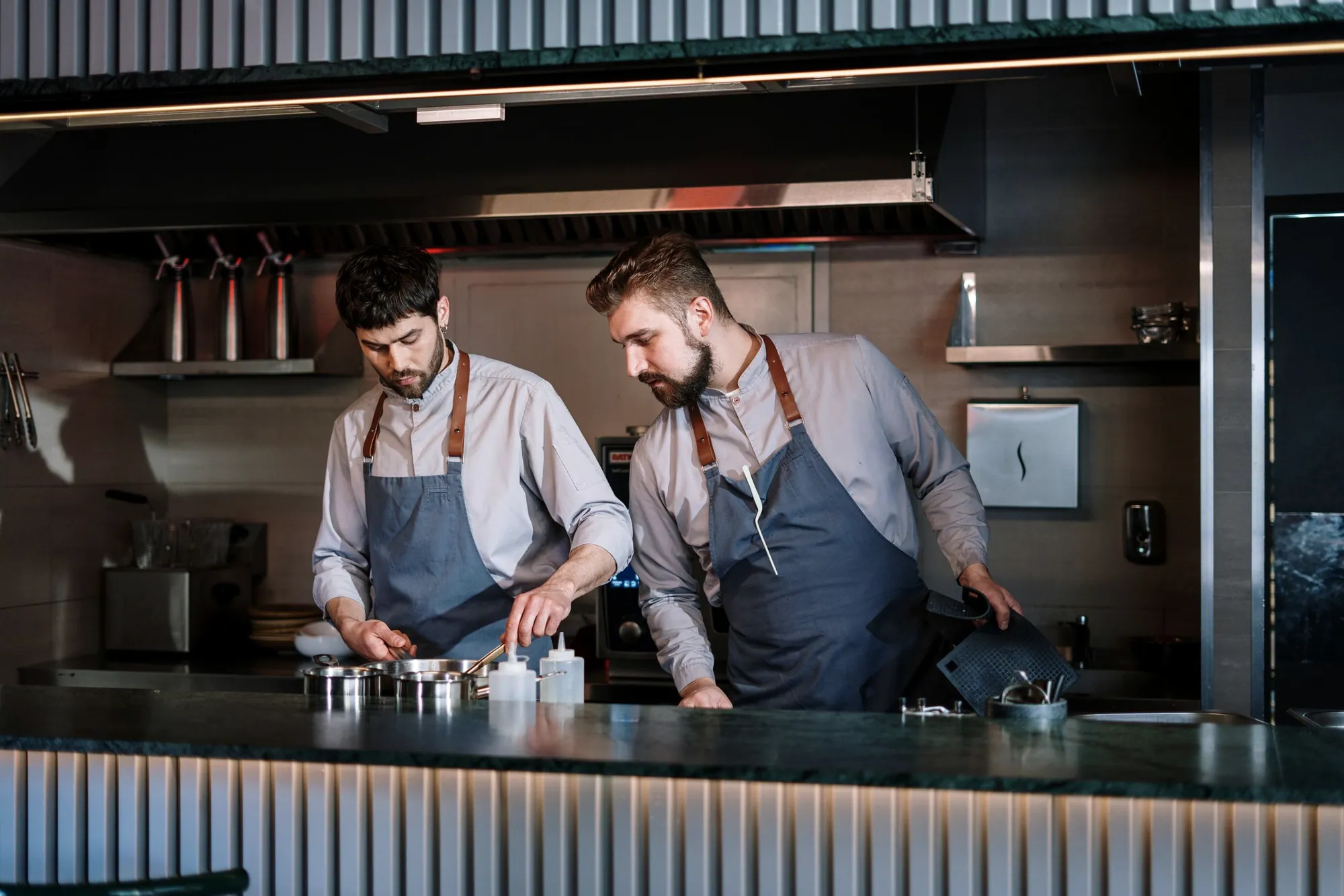 Two chefs working the line in an open restaurant kitchen