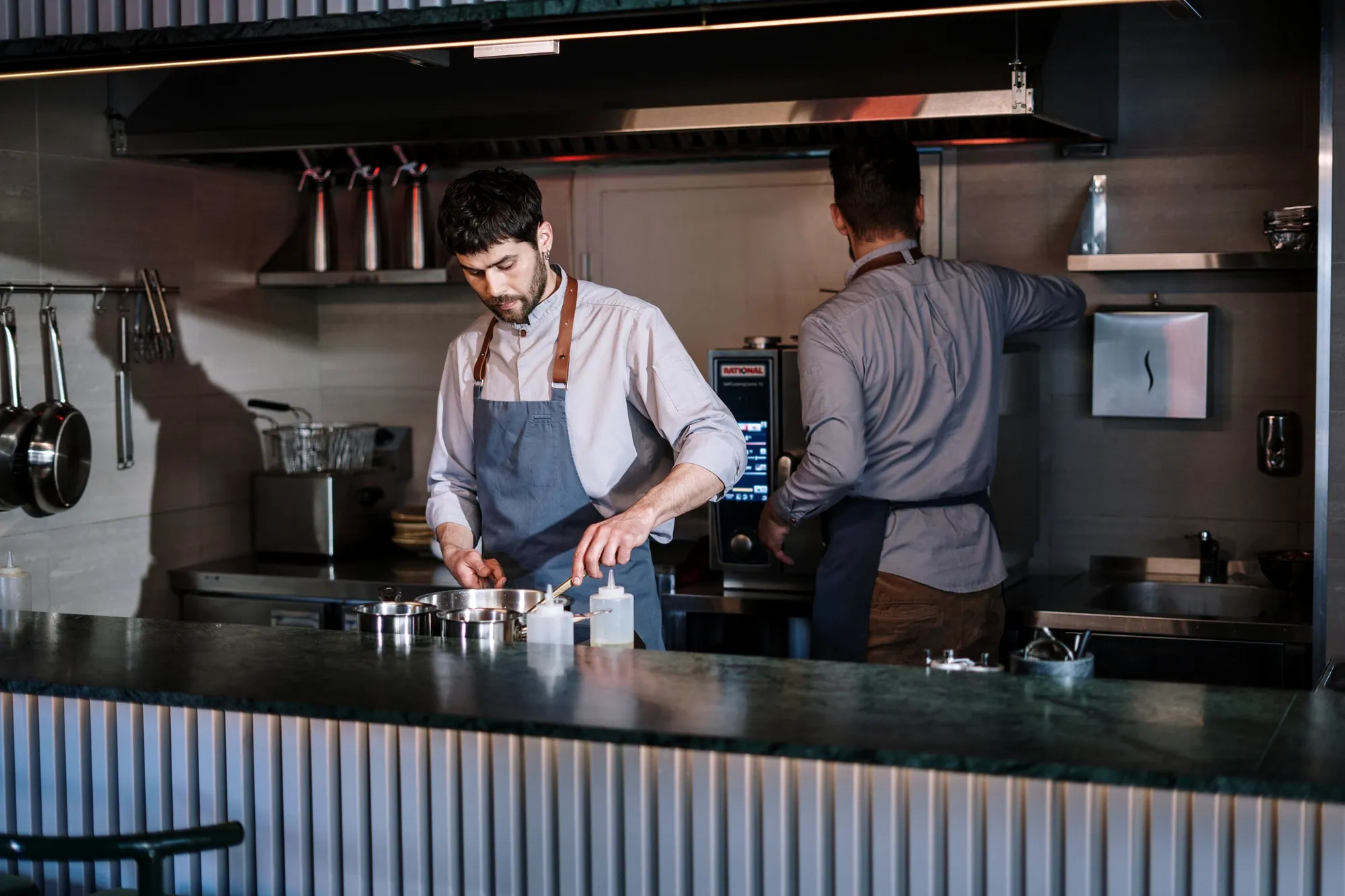 Chefs plating dishes in an open restaurant kitchen