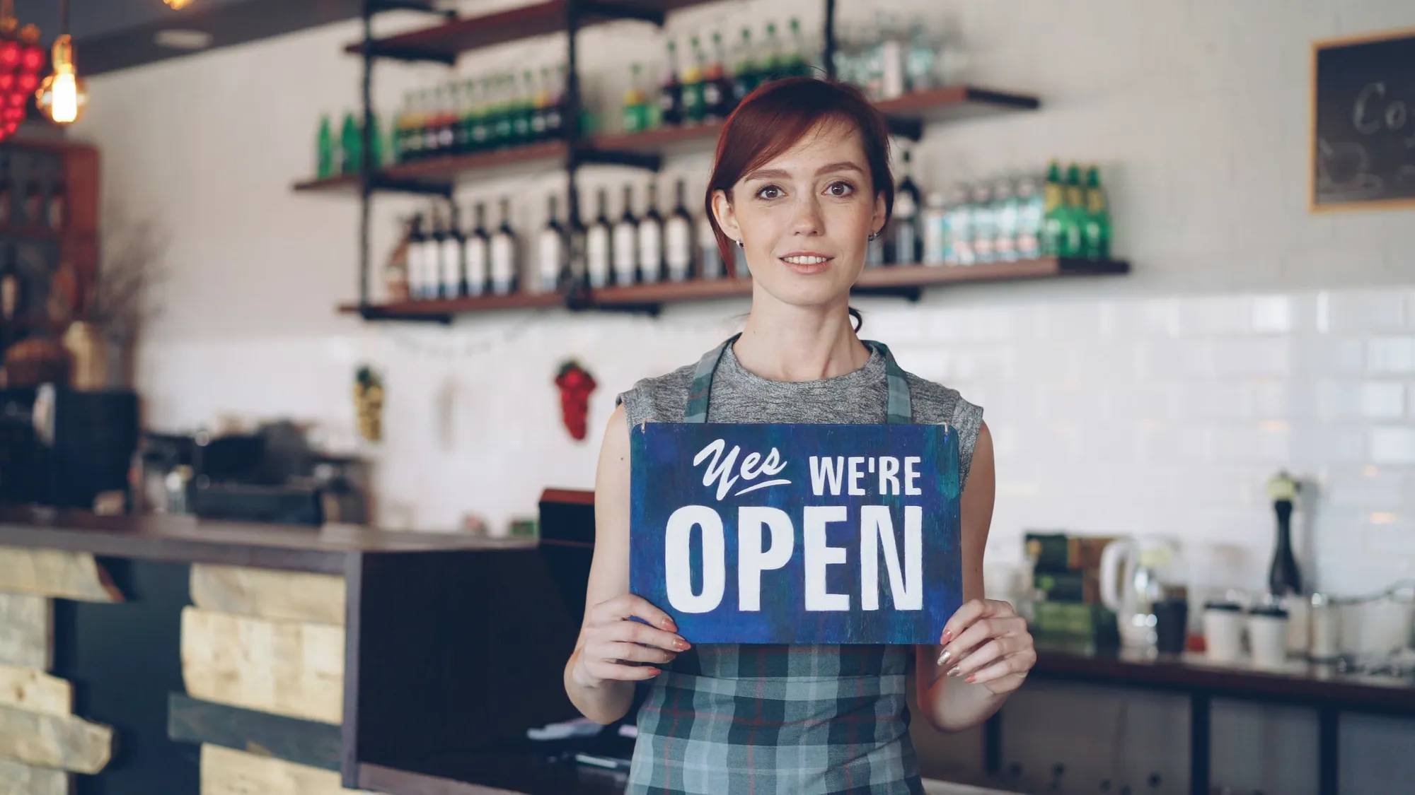 Owner holding an open sign in her cafe doorway