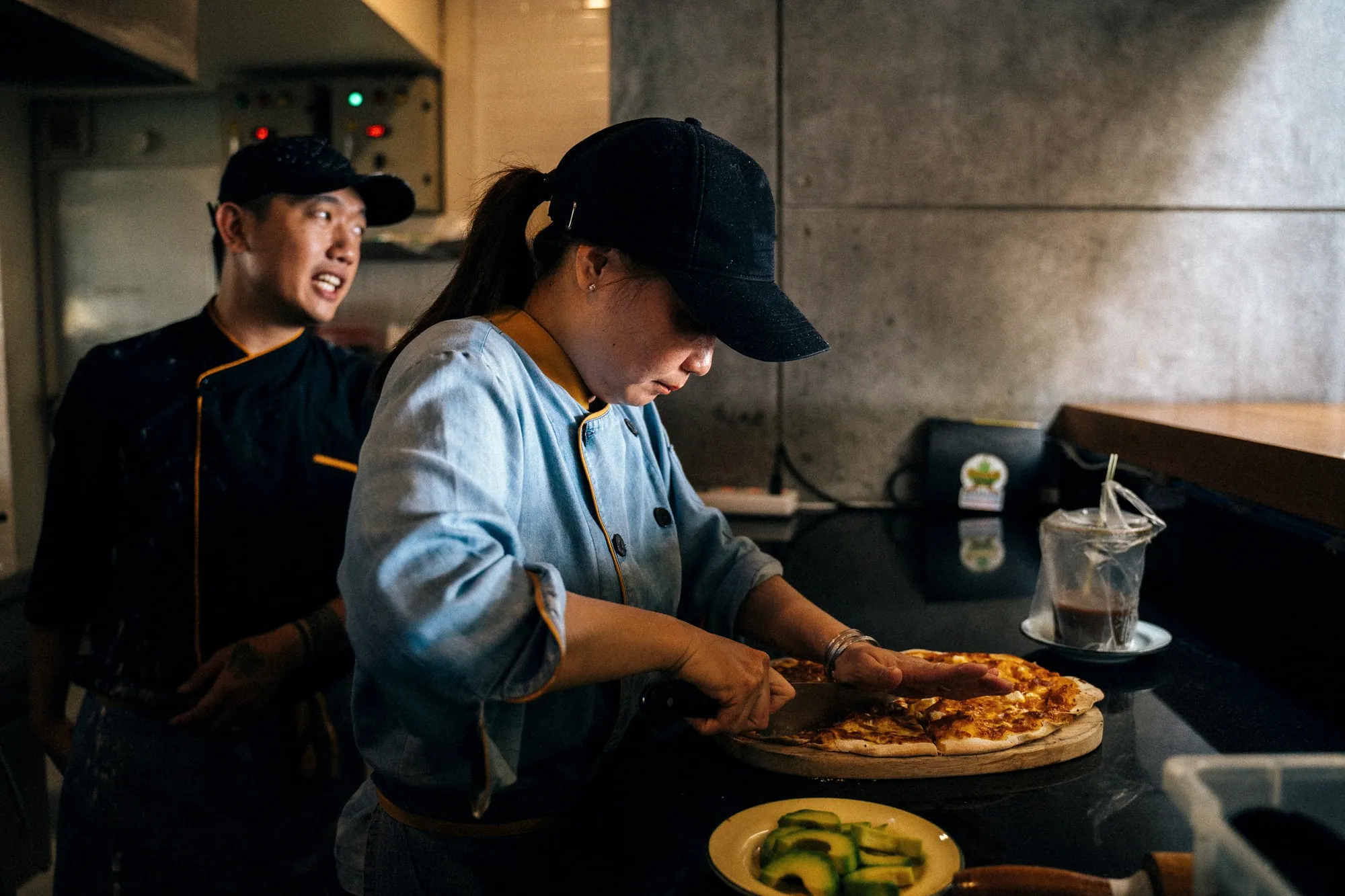 Two chefs slicing a freshly baked pizza